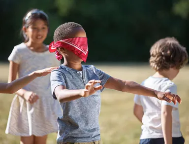 blindfold-boy-searching-friends-on-field-1057594582-686a5bc5cd0140dd8ade0201b55ad63f.jpg