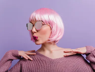 indoor-portrait-of-winsome-lady-in-sparkle-glasses-and-knitted-sweater-standing-on-purple-wall-photo-of-glamorous-girl-in-pink-wig-posing-with-kissing-face-expression.jpg